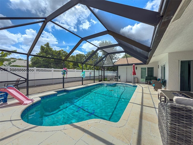 view of pool with a patio area, a fenced in pool, a fenced backyard, a water slide, and a lanai
