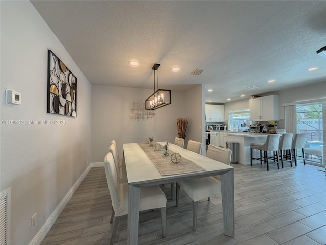 dining area with recessed lighting, a chandelier, light wood-style floors, baseboards, and a textured ceiling