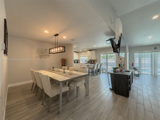 dining space featuring light wood-style floors, recessed lighting, visible vents, and baseboards