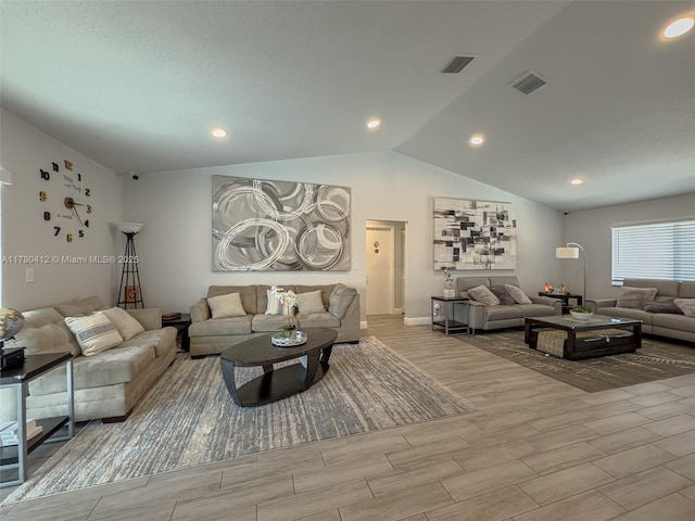 living area with wood finished floors, visible vents, vaulted ceiling, and baseboards