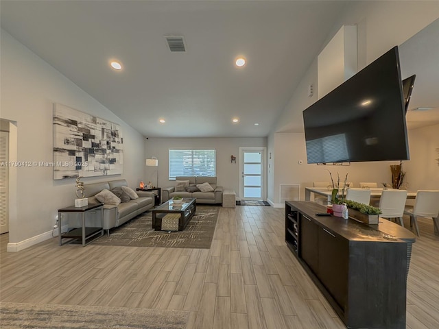 living area featuring lofted ceiling, light wood-style floors, visible vents, and baseboards
