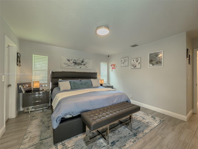 bedroom with baseboards, visible vents, and wood finished floors