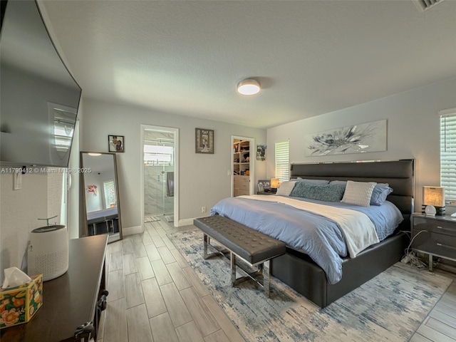 bedroom with wood tiled floor, baseboards, ensuite bath, and multiple windows