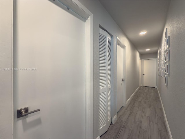 corridor featuring baseboards, recessed lighting, and wood finish floors