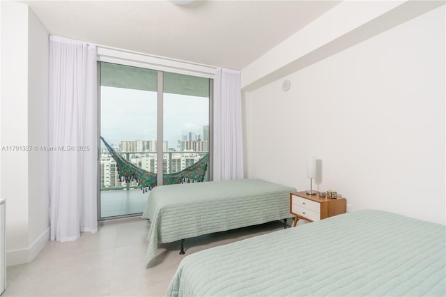 bedroom featuring a wall of windows, a view of city, access to exterior, and baseboards