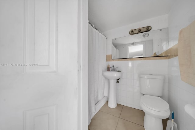 bathroom with a sink, a shower with shower curtain, toilet, tile walls, and tile patterned floors