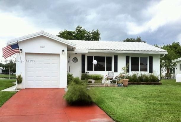 single story home with a tile roof, a front yard, stucco siding, concrete driveway, and an attached garage