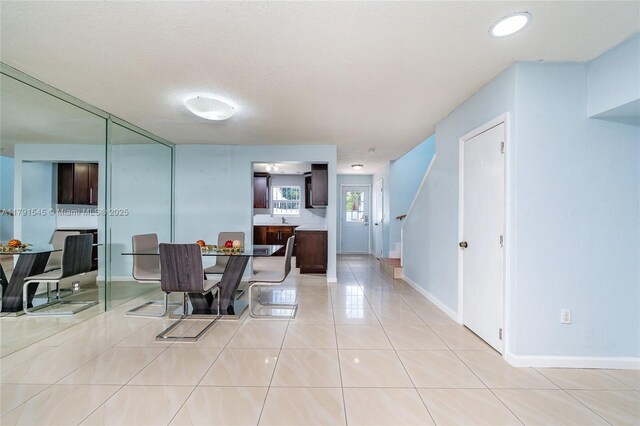 kitchen with a sink, light tile patterned floors, stainless steel appliances, and glass insert cabinets