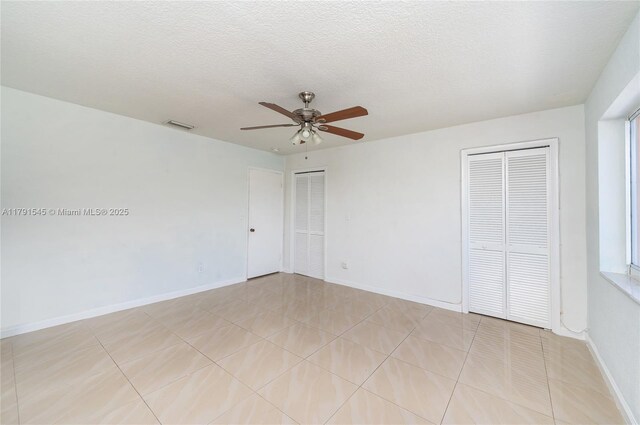 spare room with baseboards, a textured ceiling, ceiling fan, and light tile patterned floors