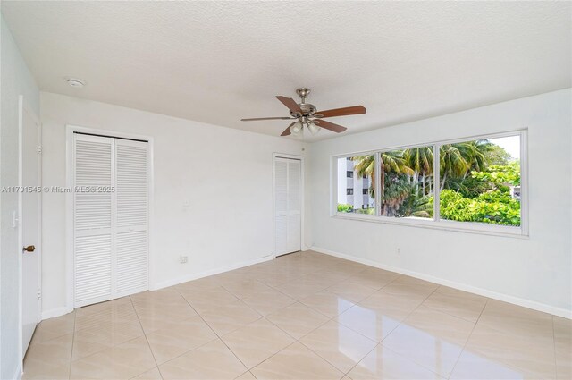empty room with a textured ceiling, ceiling fan, visible vents, and light tile patterned floors