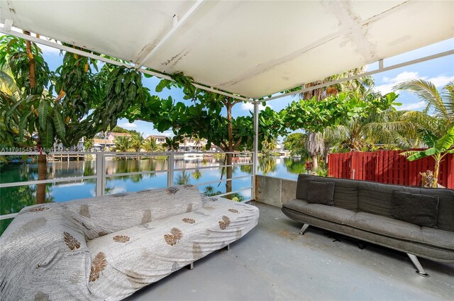view of patio featuring an outdoor living space, a water view, and fence