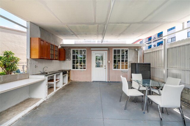 view of patio featuring outdoor dining area, fence, and a sink