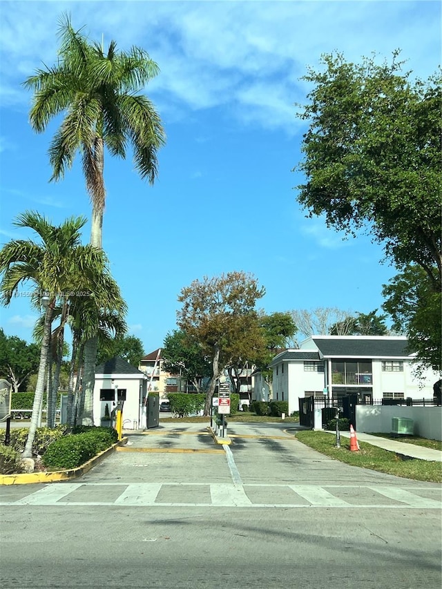 view of street featuring curbs, a speed bump, traffic signs, and a gated entry
