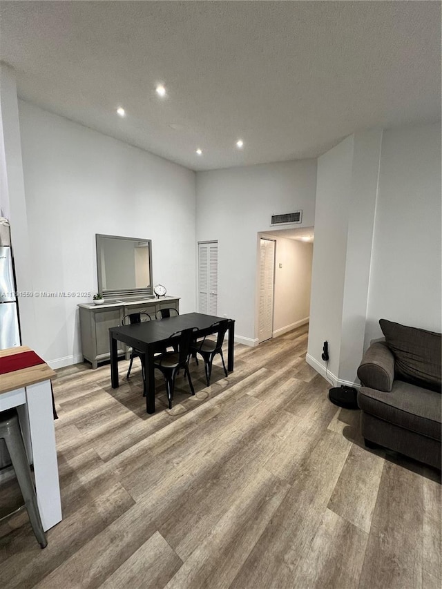 dining space featuring recessed lighting, light wood-style floors, baseboards, visible vents, and a textured ceiling