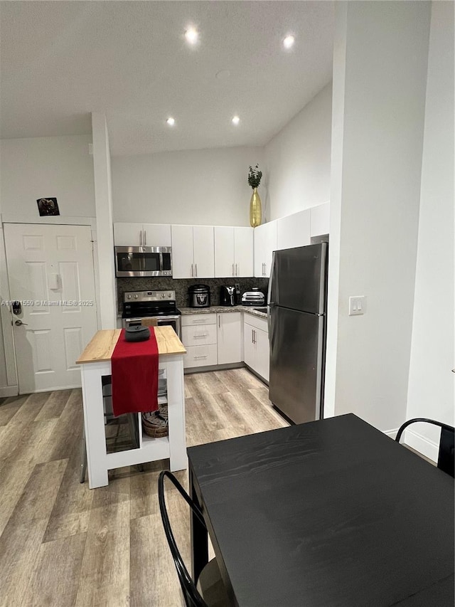 kitchen featuring tasteful backsplash, recessed lighting, stainless steel appliances, white cabinets, and light wood-type flooring