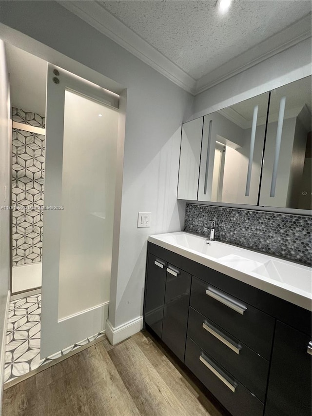 full bath with a tile shower, tasteful backsplash, crown molding, wood finished floors, and vanity
