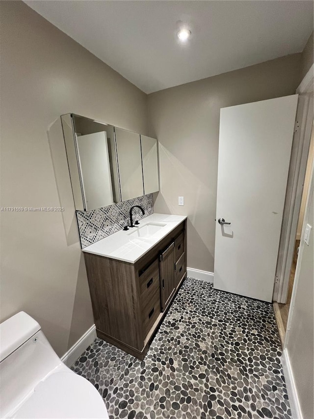 bathroom featuring baseboards, toilet, and vanity
