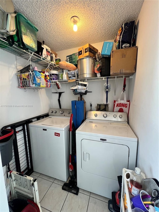 clothes washing area featuring a textured ceiling, separate washer and dryer, and laundry area
