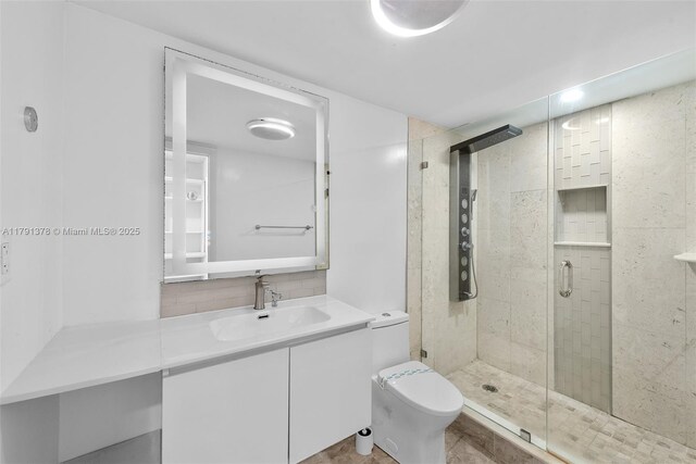 bathroom featuring toilet, a shower stall, backsplash, and vanity