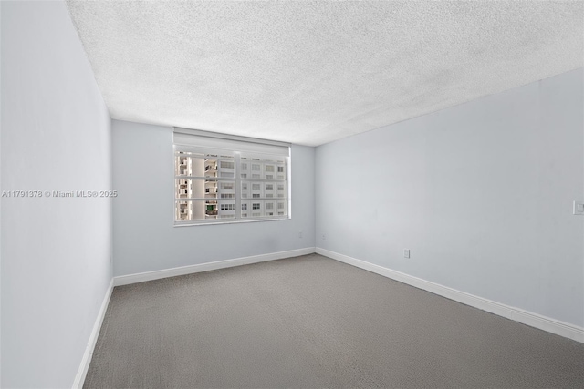 carpeted spare room featuring a textured ceiling and baseboards