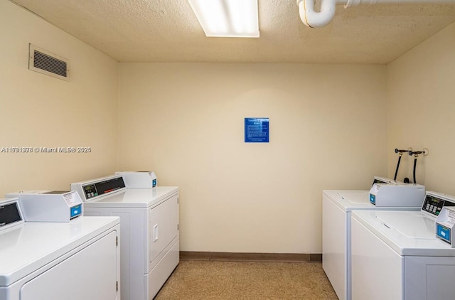 common laundry area featuring a textured ceiling, visible vents, separate washer and dryer, and light carpet