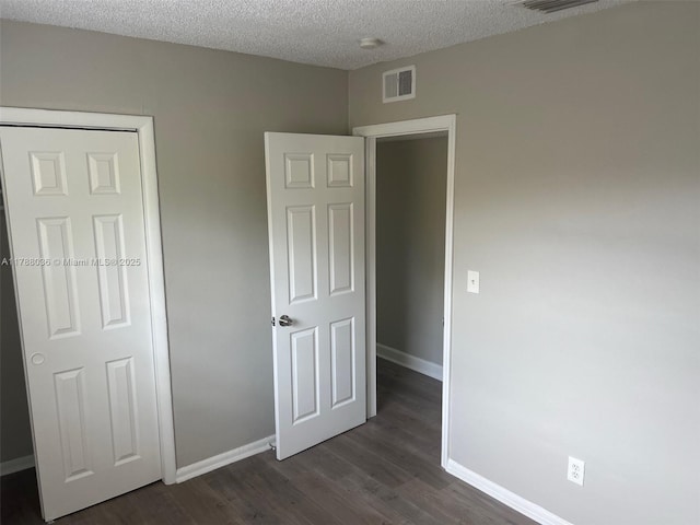 4410 NW 30th Ct, Lauderdale Lakes, FL 33313 - unfurnished bedroom with dark wood finished floors, visible vents, a textured ceiling, and baseboards