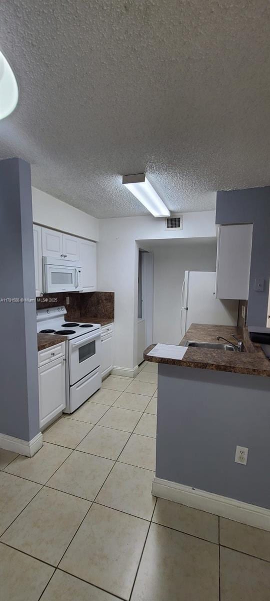 15231 SW 80th St Unit 209, Miami, FL 33193 - kitchen featuring a textured ceiling, white cabinetry, dark countertops, light tile patterned flooring, and white appliances