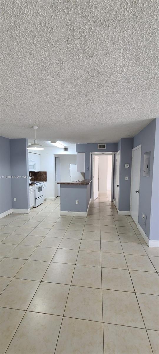 15231 SW 80th St Unit 209, Miami, FL 33193 - unfurnished living room with a textured ceiling, visible vents, light tile patterned flooring, and baseboards