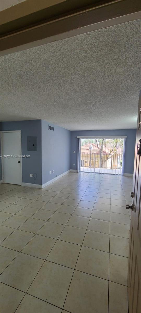 15231 SW 80th St Unit 209, Miami, FL 33193 - spare room with baseboards, visible vents, a textured ceiling, and light tile patterned flooring