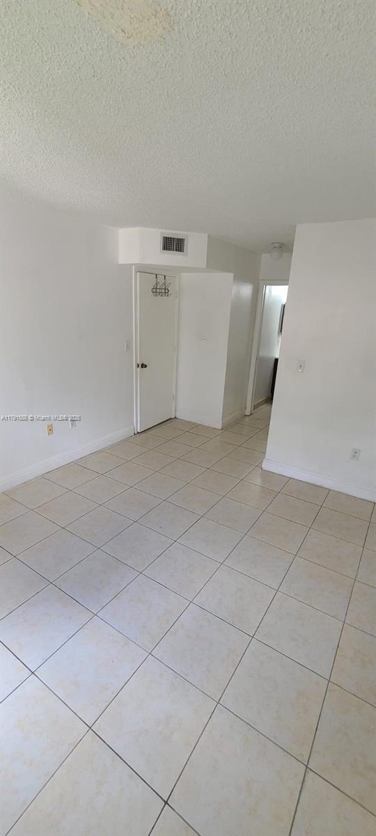 15231 SW 80th St Unit 209, Miami, FL 33193 - empty room with a textured ceiling, visible vents, light tile patterned floors, and baseboards
