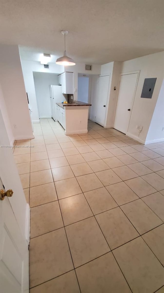 15231 SW 80th St Unit 209, Miami, FL 33193 - kitchen with light tile patterned floors, white cabinetry, dark countertops, electric panel, and freestanding refrigerator