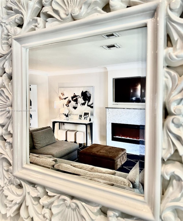 living area featuring a warm lit fireplace and crown molding