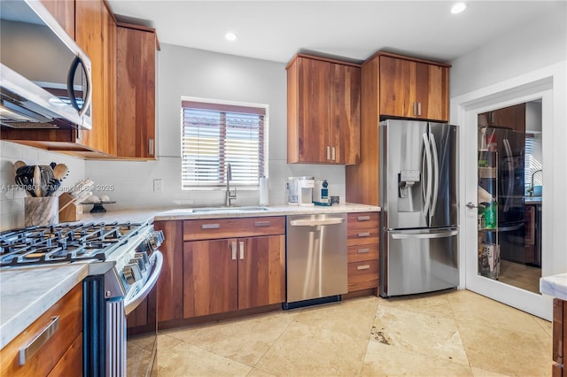 kitchen with tasteful backsplash, brown cabinetry, appliances with stainless steel finishes, light countertops, and a sink