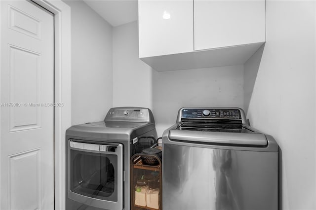 clothes washing area featuring cabinet space and washer and clothes dryer