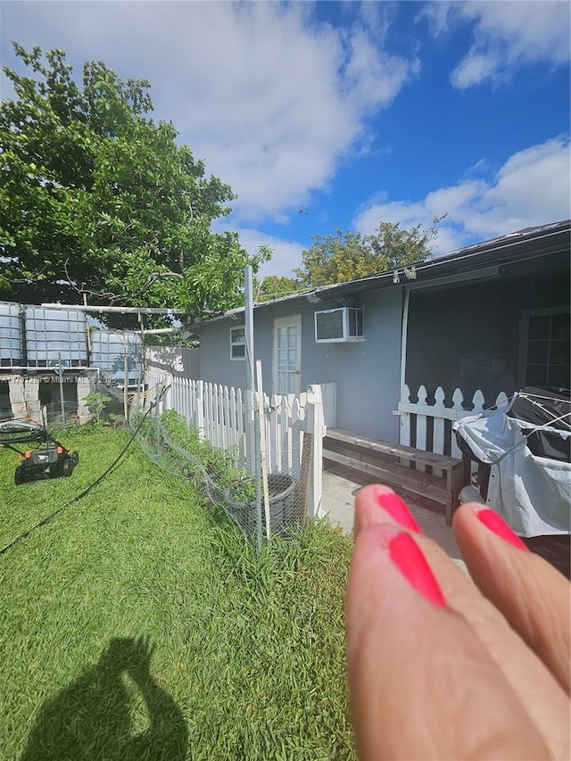 view of side of home featuring a wall mounted air conditioner, stucco siding, and fence