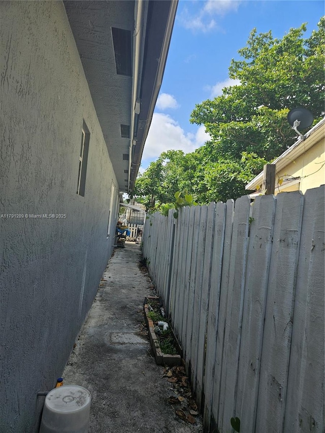 view of side of property with fence and stucco siding
