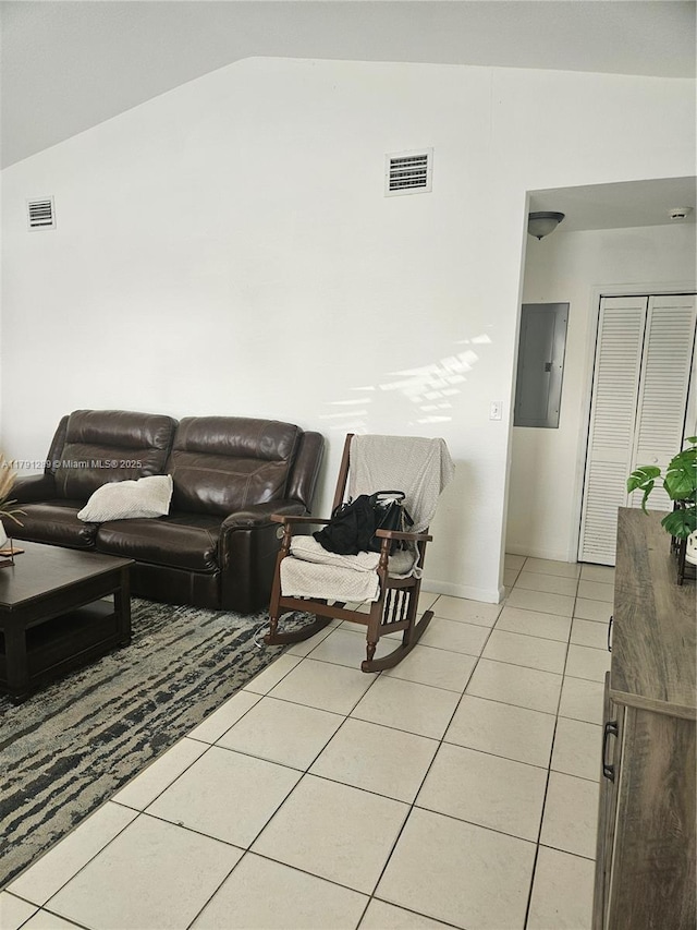 living area with light tile patterned floors, visible vents, electric panel, and vaulted ceiling