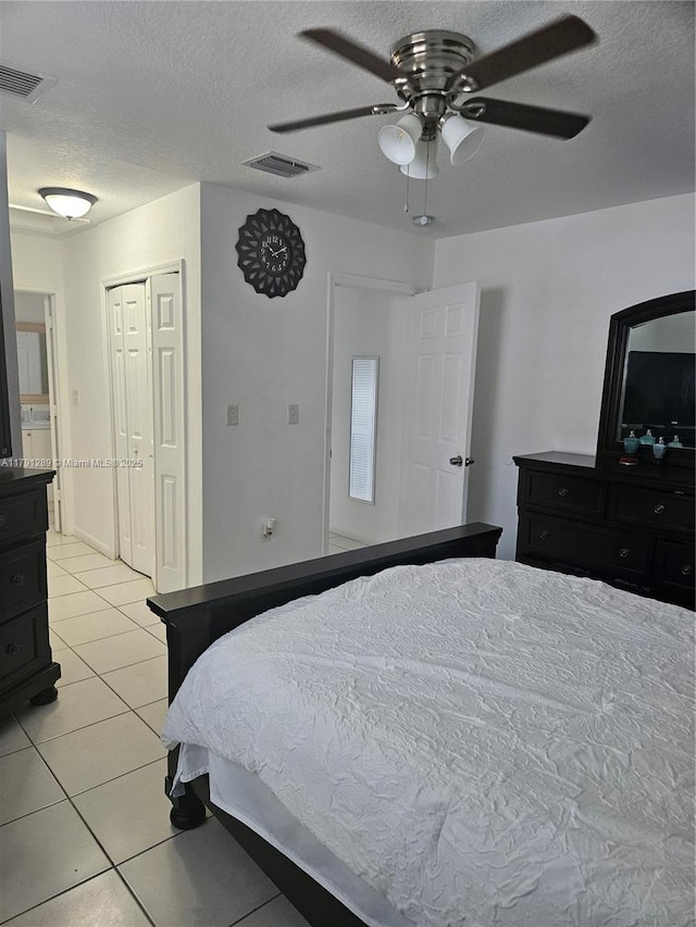 bedroom featuring light tile patterned flooring, a textured ceiling, visible vents, and a ceiling fan