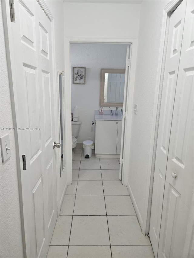 bathroom with toilet, tile patterned flooring, vanity, and baseboards