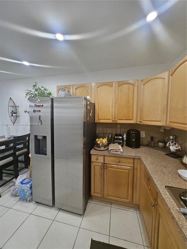 kitchen with light tile patterned flooring, stainless steel refrigerator with ice dispenser, electric cooktop, and light brown cabinets