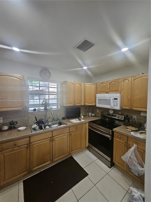 kitchen featuring a sink, light tile patterned flooring, stainless steel range with electric cooktop, visible vents, and white microwave
