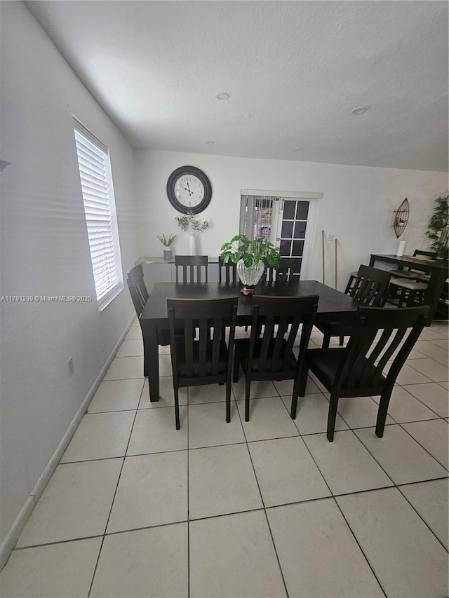 dining room with light tile patterned flooring, baseboards, and a textured ceiling
