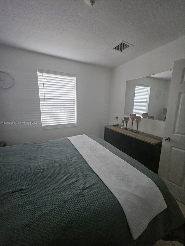 bedroom with a textured ceiling and visible vents