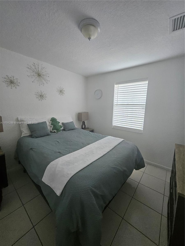 tiled bedroom with a textured ceiling and visible vents