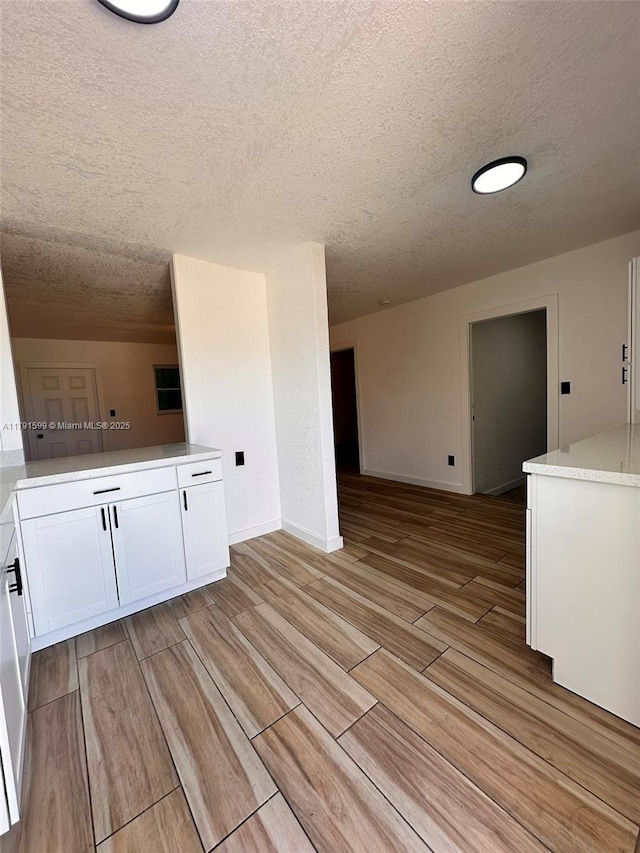 249 SW 4th Ct, Homestead, FL 33030 - kitchen with a textured ceiling, wood finish floors, white cabinetry, light countertops, and baseboards
