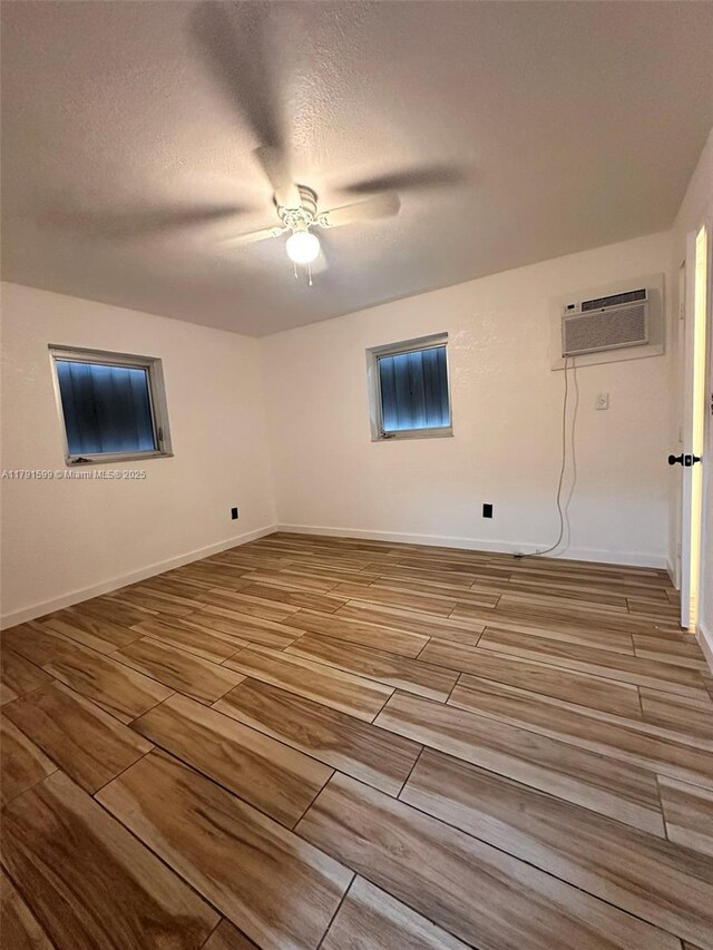 249 SW 4th Ct, Homestead, FL 33030 - empty room with a wall mounted air conditioner, wood tiled floors, a ceiling fan, baseboards, and a textured ceiling