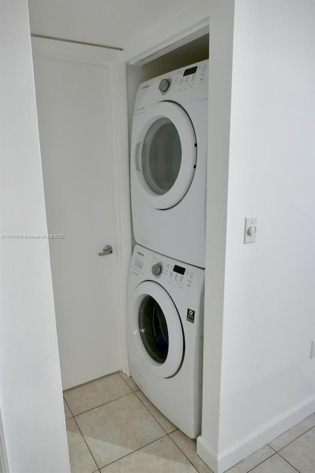 clothes washing area with stacked washer and dryer, light tile patterned flooring, and laundry area