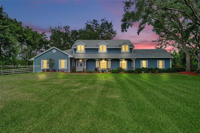country-style home featuring a lawn, fence, and a porch