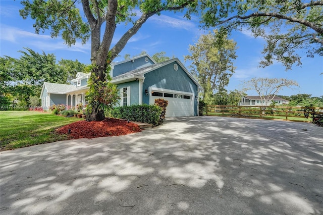 view of side of property featuring an attached garage, a yard, fence, and driveway