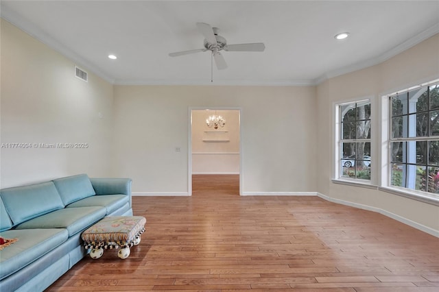 living area featuring visible vents, ornamental molding, baseboards, light wood finished floors, and ceiling fan with notable chandelier